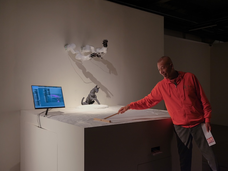 蔡国强与交互装置《cAI™️占卜屋》，“cAI™️：灵魂扫描”展览现场，澳门海事工房1号，2024年。赵梦佳摄，蔡工作室提供。